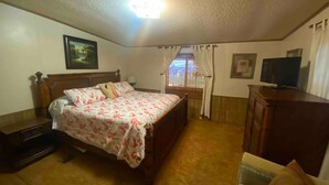 A bedroom with a bed, a television, a desk, and a window with curtains. - Beautiful  Water Front  Cabins (Georgetown)