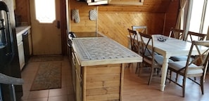 A wooden interior with a kitchen area, including a stove, oven, and a dining table with chairs. - Cherokee Lake, 3bed/2bath (Talbott)