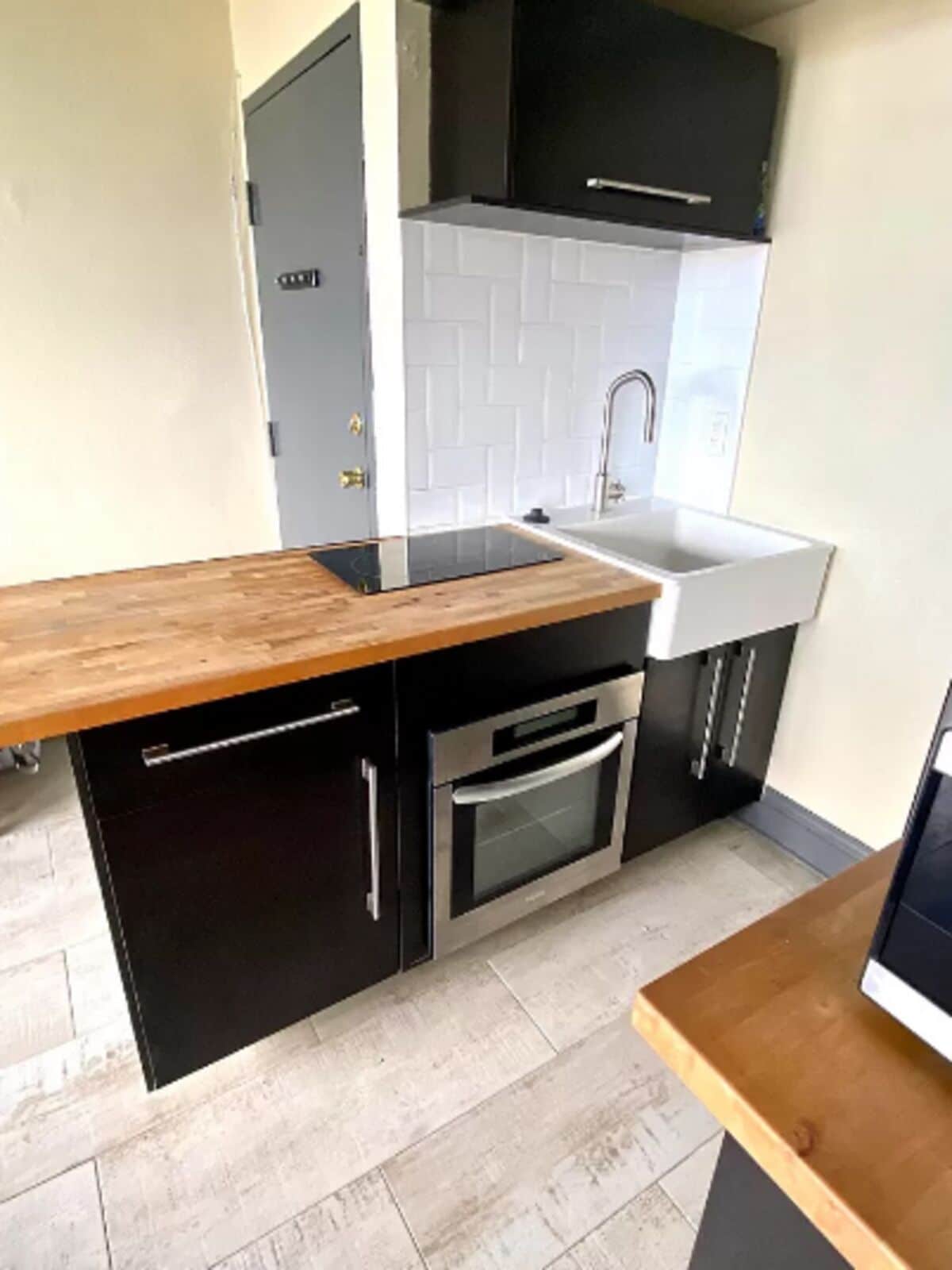 Une cuisine compacte dotée d’un plan de travail en bois, d’un four encastré et d’un évier.