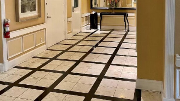Ein Hotelkorridor mit Schachbrettboden, einem großen Spiegel und einem Feuerlöscher an der Wand.