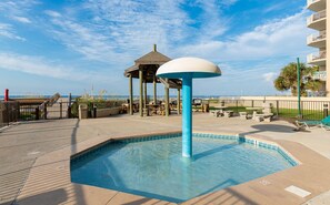 Uma área de piscina com um gazebo, espreguiçadeiras e vista para o oceano.