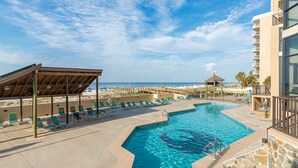 A pool area with lounge chairs, a covered seating area, and a view of the beach. - Beachfront Condo w Private Balcony in Orange Beach, AL at PHX I (Orange Beach)