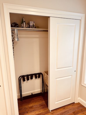 A closet with a hanging rack, a shelf with a box, and a door.