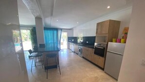 A modern kitchen with a dining area, a washing machine, and a refrigerator. - private Villa Marrakech : Villa nahellan (Marrakech)