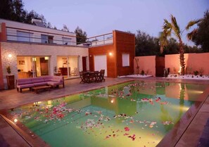 Una casa moderna amb piscina, zona d'estar a l'exterior i un balcó.