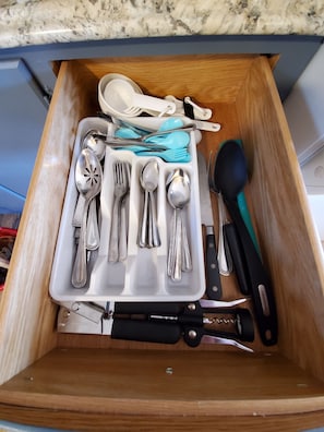 A drawer containing various kitchen utensils including spoons, forks, and knives.