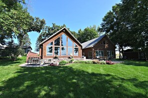 Une maison en bois à deux étages, dotée de grandes fenêtres et d’une fondation en pierre.