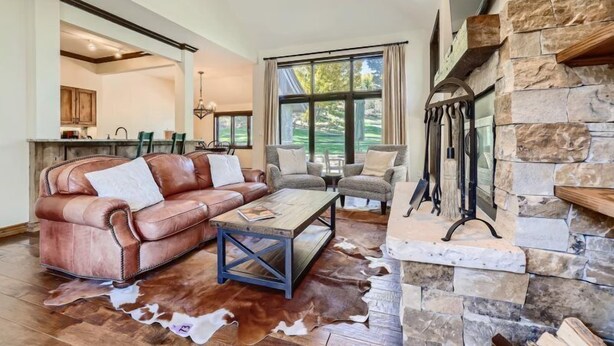 A spacious living room with a leather sofa, a coffee table, and a stone fireplace. - 1-10 N. Fairway Drive (Avon)