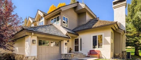 A two-story house with a garage, stone foundation, and a well-maintained lawn.