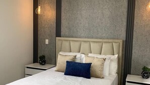A modern bedroom with a large bed, two bedside tables, and a ceiling light fixture. - Beautiful view, 13th floor, modern, exclusive and comfortable apartment. (Santiago De Los Caballeros)