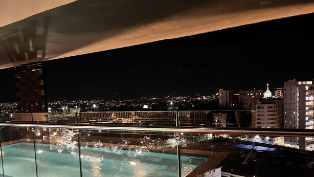 A rooftop pool with a glass barrier, city lights in the background, and buildings across the water. - Beautiful view, 13th floor, modern, exclusive and comfortable apartment. (Santiago De Los Caballeros)