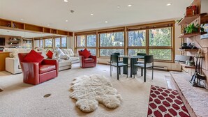 Un salón amplio con un ventanal grande, una chimenea y una zona de comedor.