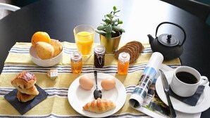 Ein Frühstücksarrangement mit Früchten, Eiern, Toast und Getränken auf einem Tisch mit kariertem Tischläufer.