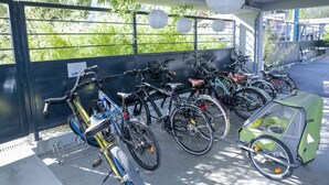 Ein überdachter Fahrradstellplatz mit verschiedenen Fahrrädern und einem kleinen, grünen Versorgungsfahrrad.