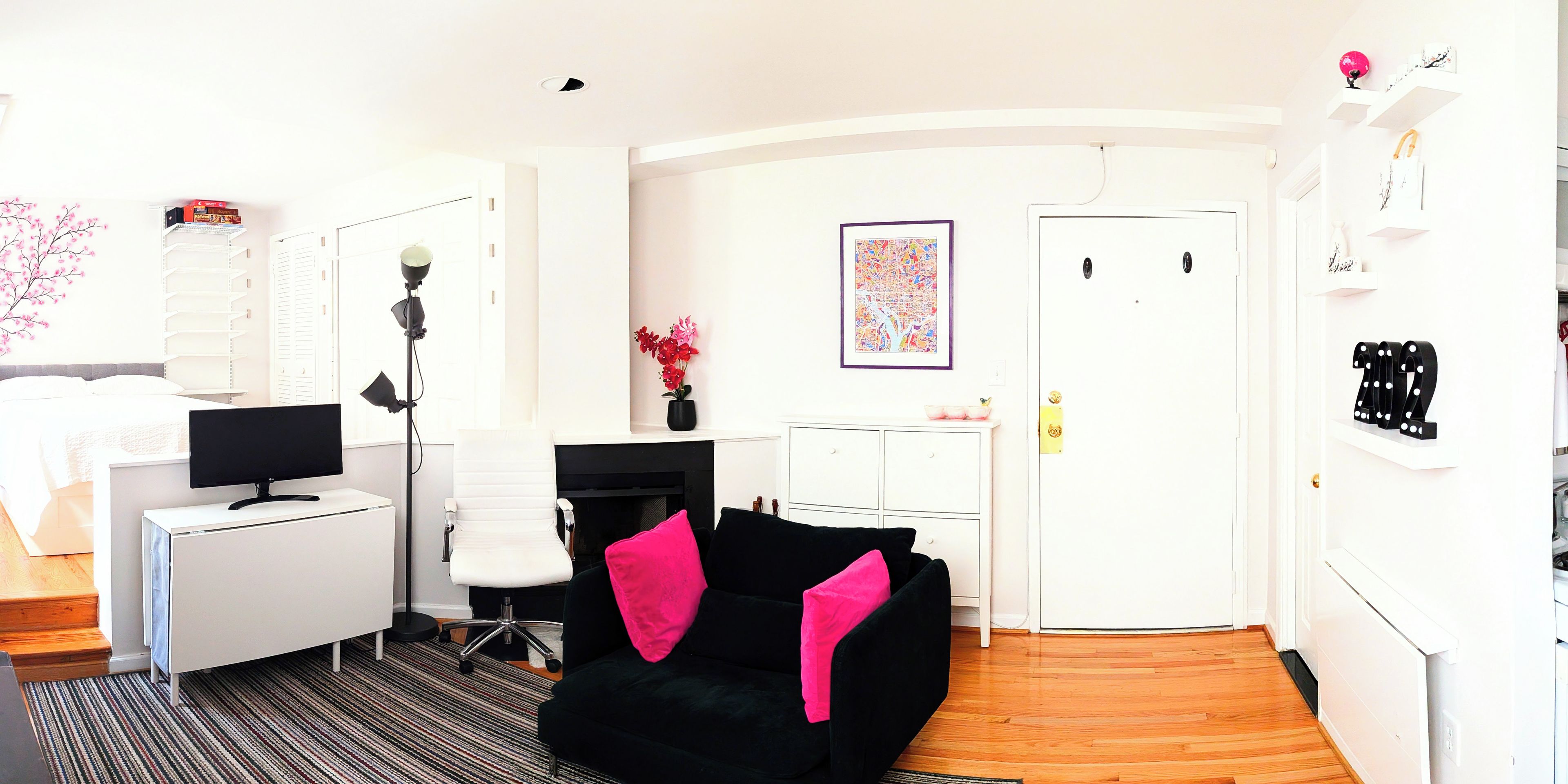 A modern living room with a black sofa, a white desk, and a computer monitor.