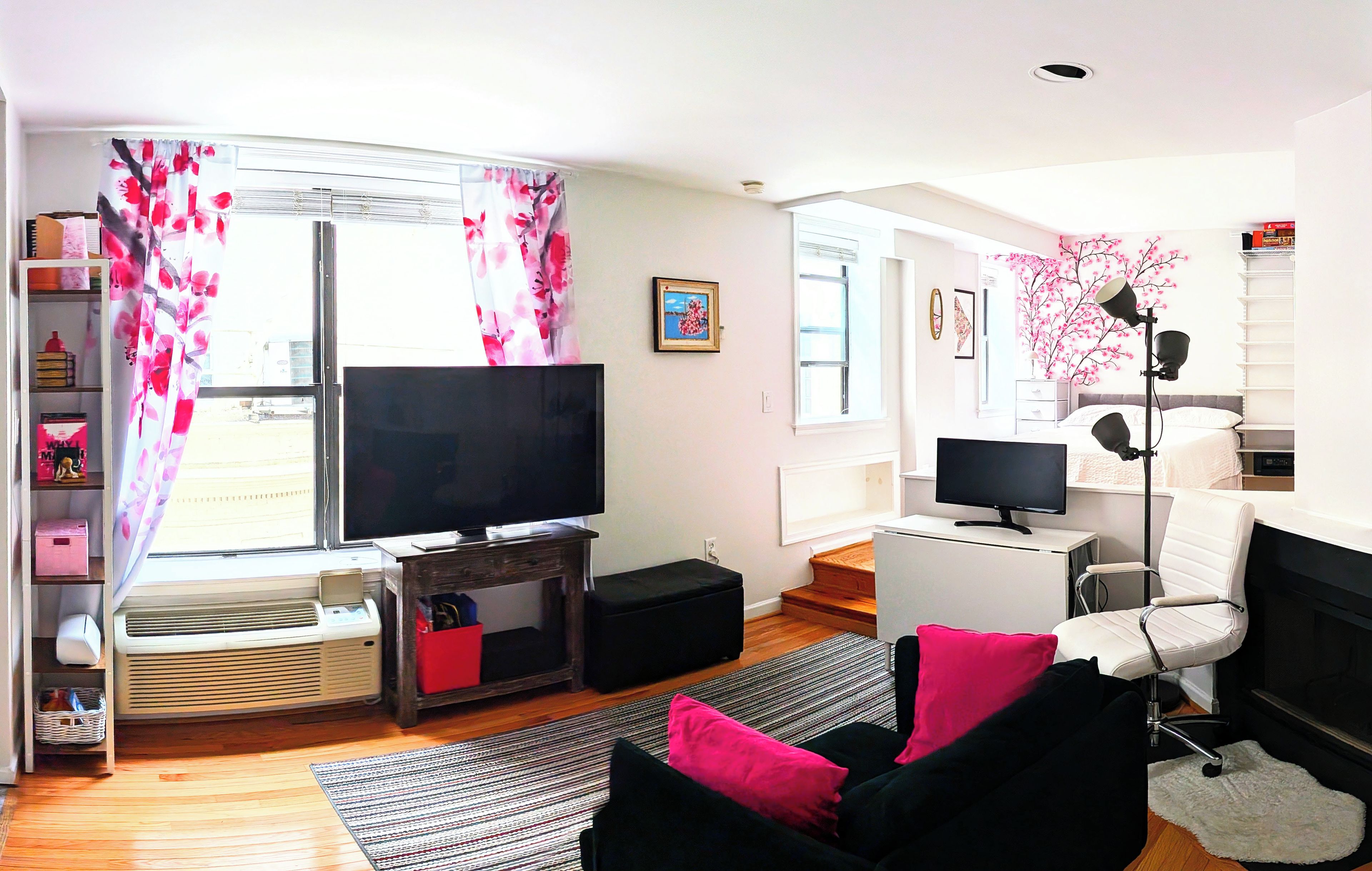 A modern living room with a flat-screen TV, a sofa, a chair, and a small table.