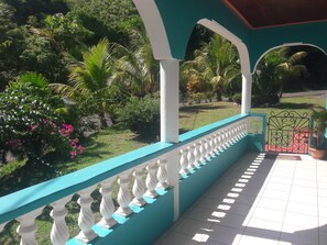 A covered outdoor area with a turquoise railing, white balusters, and a tiled floor.