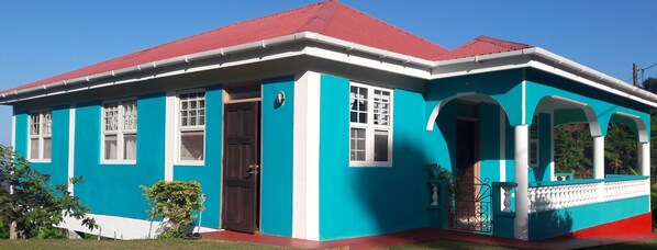 Ein zweigeschossiges Haus mit rotem Dach, blauen Außenwänden und weißer Verkleidung.