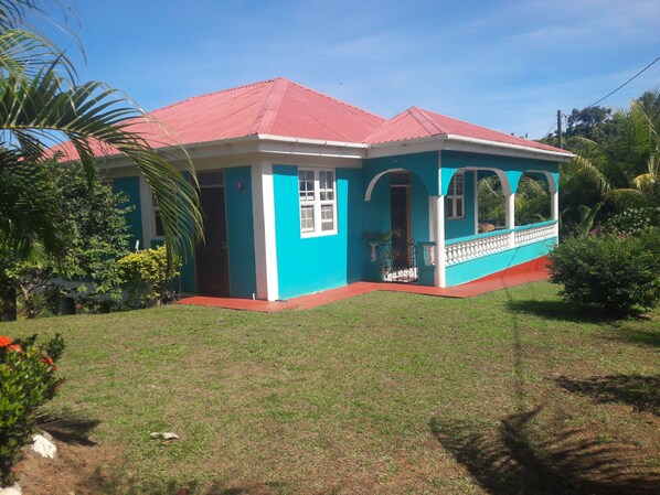 A two-story building with a red roof, blue exterior walls, and a covered porch with a railing.