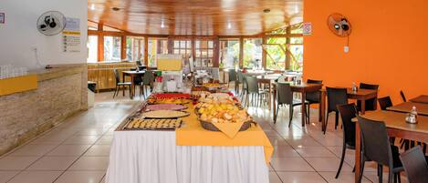 A buffet setup with various food items and a long table covered with a white tablecloth.