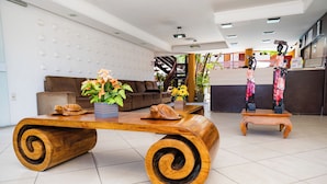 A spacious lobby with a large wooden coffee table, a brown sofa, and a small wooden table with a vase of flowers. - Hotel Casa Blanca Porto Seguro (Porto Seguro)