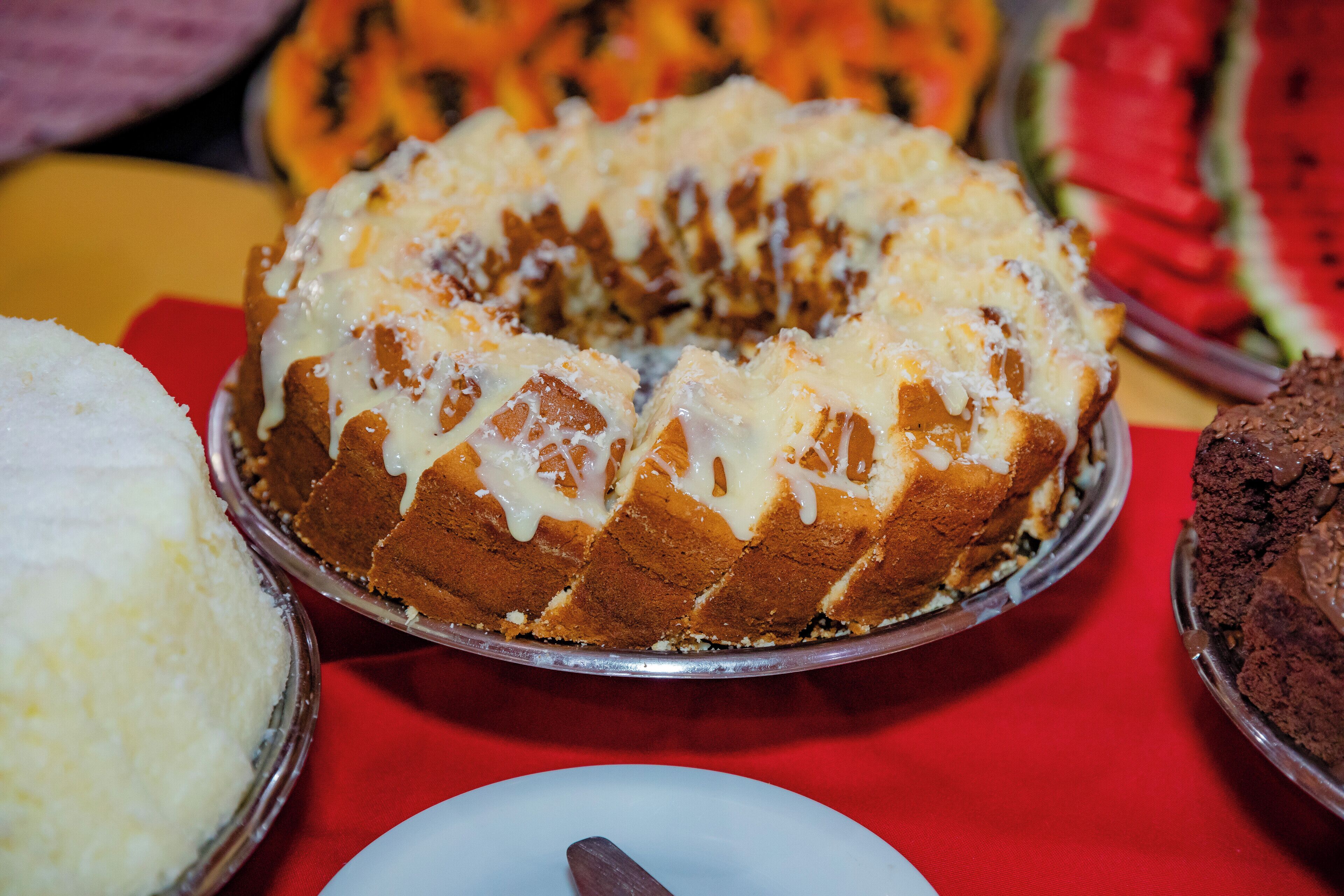 Una mesa de postres con un pastel bundt, helado y una porción de sandía.