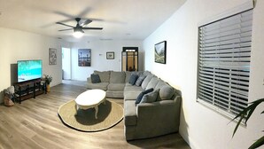 A living room with a TV, sofa, and a ceiling fan.