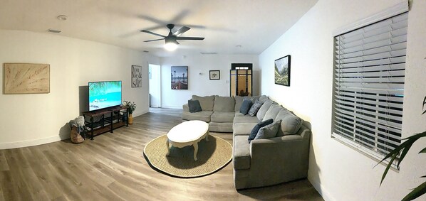 Un salon avec un téléviseur, un canapé et un ventilateur de plafond.