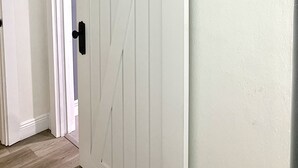 A white sliding barn door with black hardware, a wooden floor, and a white wall.