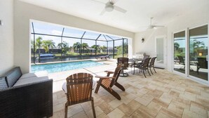 Zona de piscina con cerramiento de vidrio, asientos exteriores y ventiladores de techo.