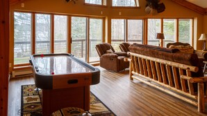 A pool table in a room with large windows, a wooden bench, and a sofa.