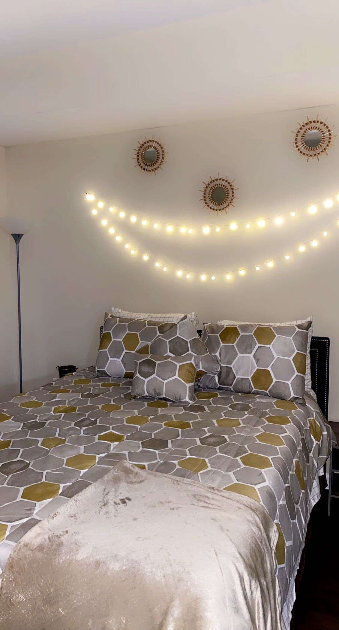 A bedroom with a bed, decorative wall lights, and patterned bedding.