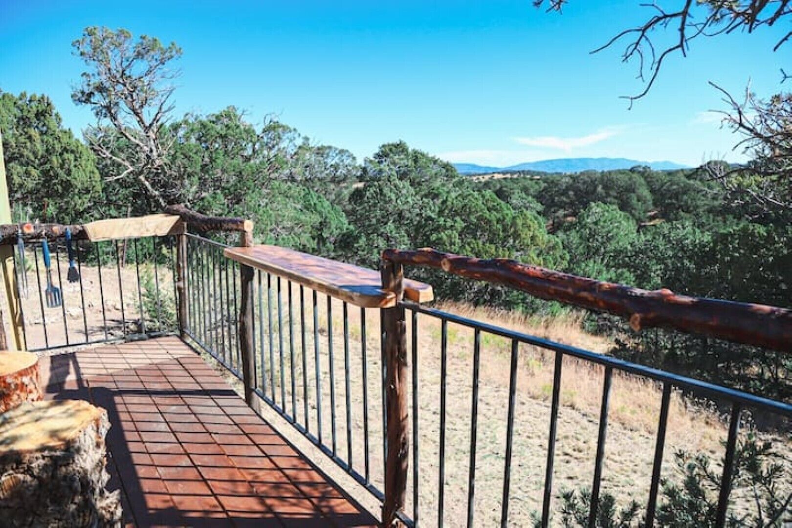 A wooden deck with metal railings overlooking a forested landscape.