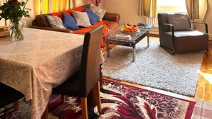 A living room with a sofa, armchairs, a coffee table, and a dining table.