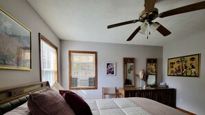 A bedroom with a large bed, a ceiling fan, a dresser, and a mirror.