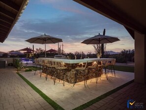 Relax in the serene outdoor patio with a bar and seating area, surrounded by a beautifully landscaped garden.