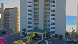 Ein mehrstöckiges Hotel namens Tropical Winds mit einem zentralen Eingang, Balkonen in jeder Etage und Blick auf den Ozean.
