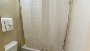 A small bathroom with a toilet, a shower curtain, and a bathtub.