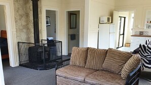En opholdsstue med sofa, pejs og et køkken i baggrunden.