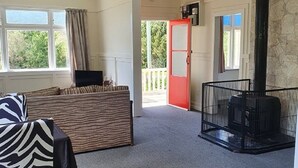 En rummelig stue med sofa, et bord med et borddække med zebra-mønster, pejs og udsigt til det fri.