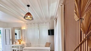 A bedroom with a bed, bedside tables, a lamp, a TV, and a large window with curtains. - Rêves de Soleil: Sweet Sunset Lodge with panoramic sea view (Sainte-Anne)