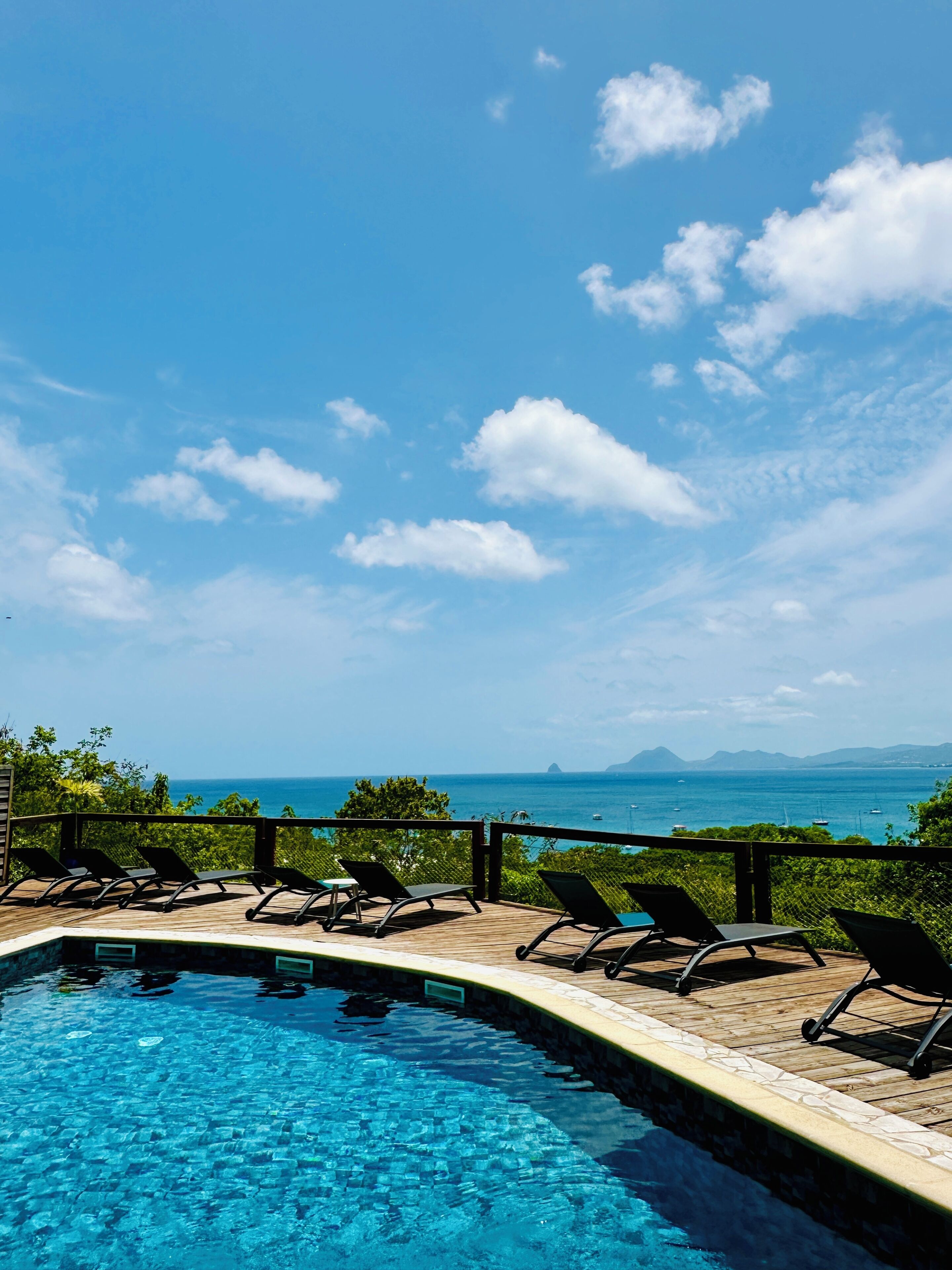 Une piscine avec des chaises longues et vue sur l’océan.