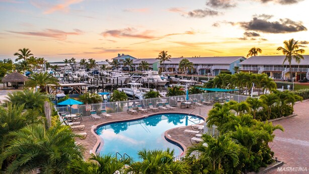 A marina with boats, a swimming pool, and resort buildings.