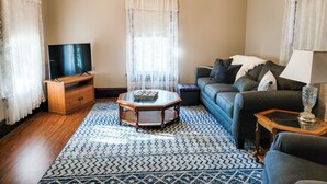 A living room with a TV, sofa, coffee table, and patterned rug. - Country house minutes from Aggieland  (College Station)