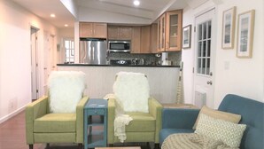 Un espai habitable compacte amb una cuineta, dos seients còmodes, un sofà i una taula de cafeteria petita.