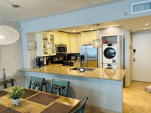 A modern kitchen with granite countertops, stainless steel appliances, and a central island.