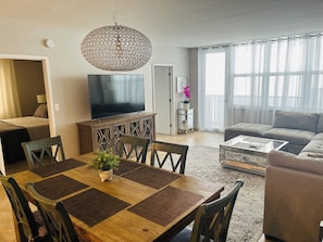 A modern living room with a dining area, a television, and a sofa.