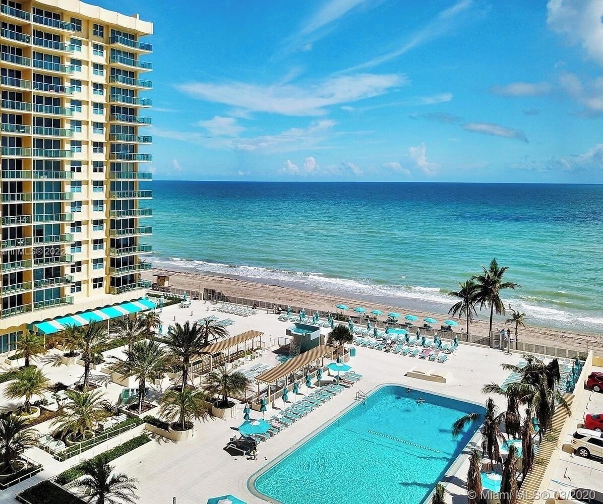 A hotel with a pool, beach, and ocean view.