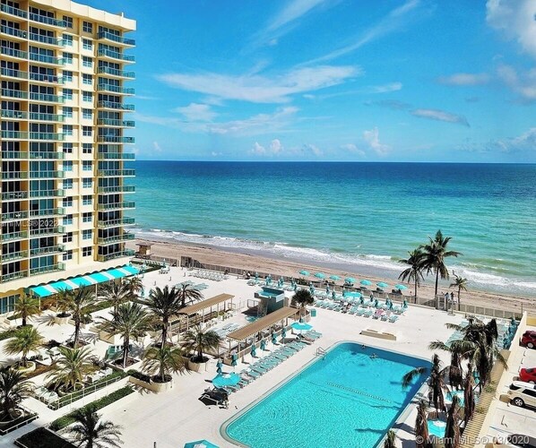 A hotel with a pool, beach, and ocean view.