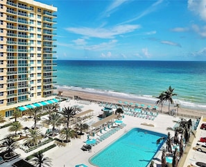 A hotel with a pool, beach, and ocean view.